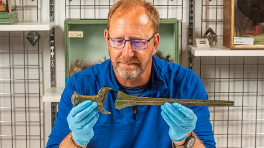 John Belgrove examines two parts of the sword he discovered